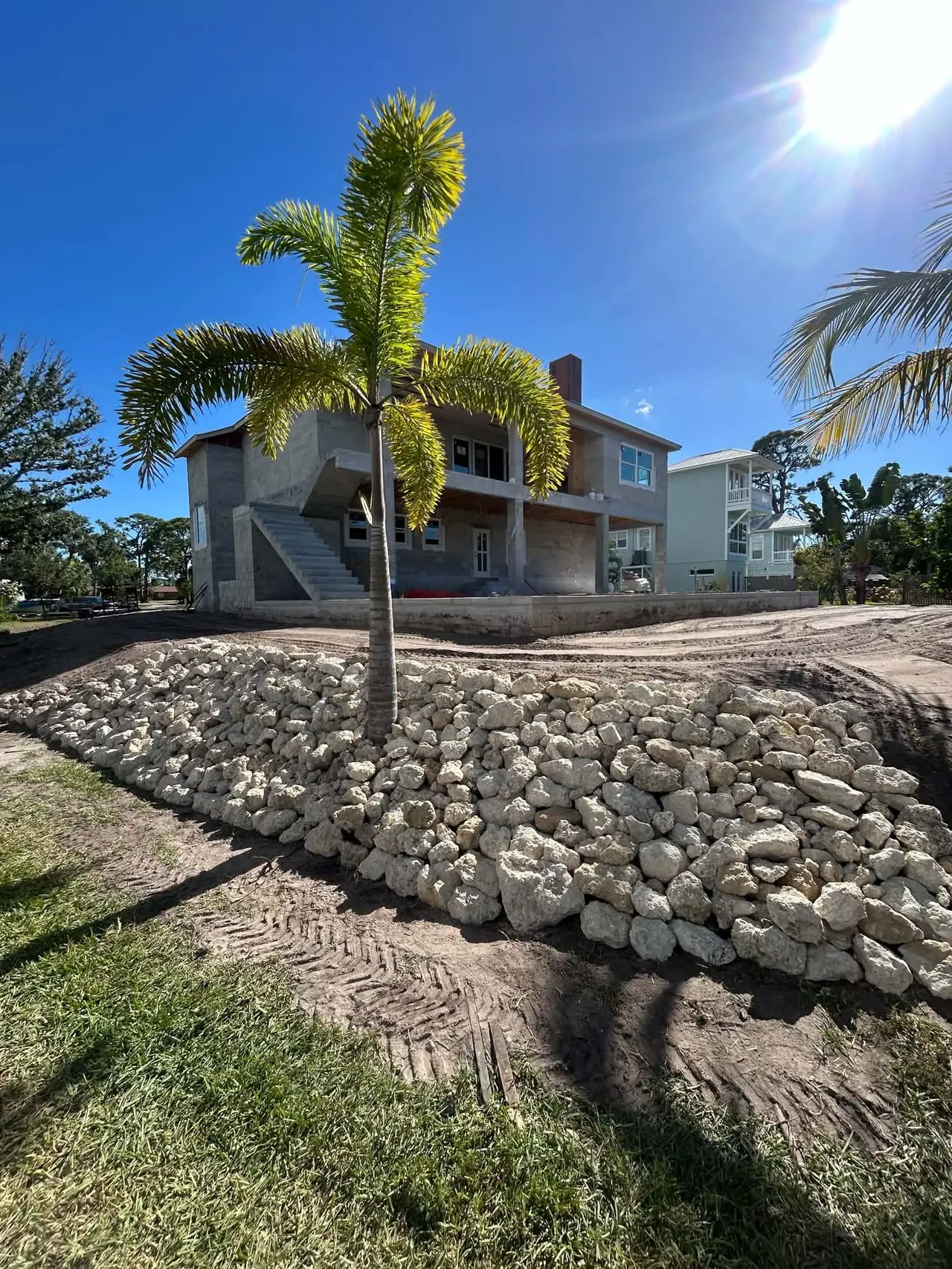 Fresh limestone rip-rap and a new royal palm on a graded lot
